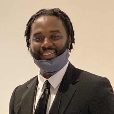 a man wearing a suit and tie smiling at the camera