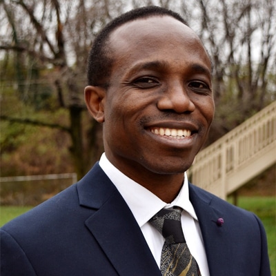 a man wearing a suit and tie smiling at the camera