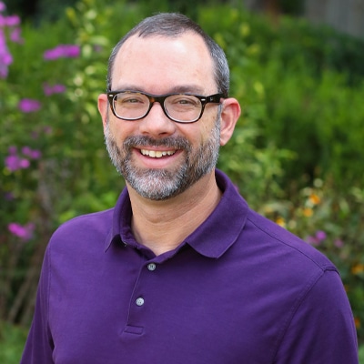 a man wearing glasses and smiling at the camera