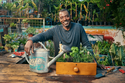 Ron Finley Sitting At A Table In Front Of A Fruit Stand